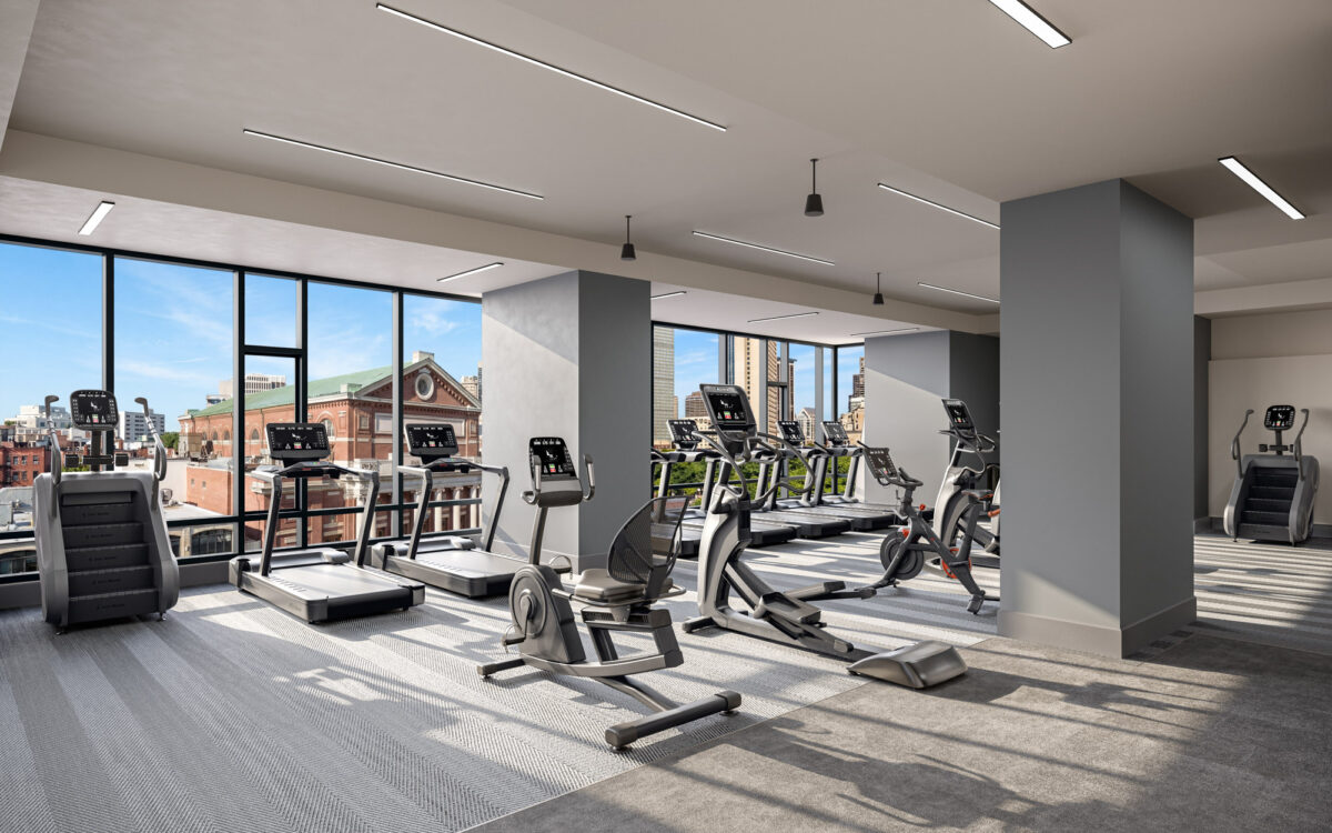 Bright fitness center with cardio equipment and large windows overlooking city